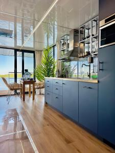 a kitchen with blue cabinets and a view of the ocean at Domki na wodzie - Resort 36 Houseboats in Giżycko
