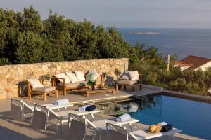 a swimming pool with lounge chairs next to a stone wall at Villa MaR-sea view,private pool in Orasac