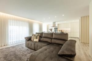 Apartamento Bela Vista - Minho's Guest في إسبونسيندي: غرفة معيشة مع أريكة بنية ومطبخ