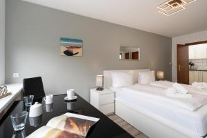 Schlafzimmer mit einem großen weißen Bett und einem Schreibtisch in der Unterkunft Adrian 3 in Westerland