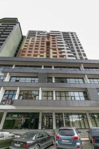 トビリシにあるCozy Berbuki Apartmentの高層ビルの前に停車した車2台 +1枚の写真
