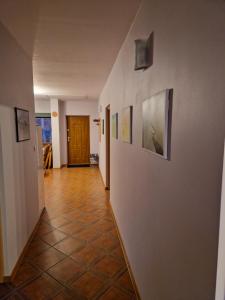 korytarz z obrazami na ścianach i podłogą wyłożoną kafelkami w obiekcie Sosnowy Młodnik w Płaskiej