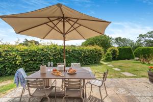 a wooden table with an umbrella on a patio at Chestnut Lodge in East Dean
