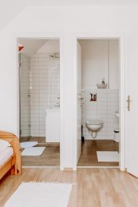 a white bathroom with a toilet and a sink at Kék Vendégház Family Resort in Gyenesdiás