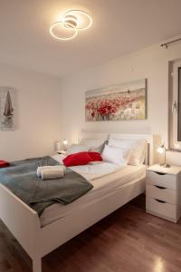 una camera da letto con un grande letto bianco e un dipinto di Pool apartment Adriana a Pag