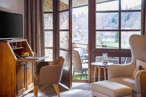 a room with a large window with chairs and a television at Lindner Hotel Oberstaufen Parkhotel, part of JdV by Hyatt in Oberstaufen