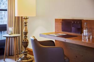Cette chambre d'hôtel dispose d'un bureau avec une lampe et des chaises. dans l'établissement Lindner Hotel Oberstaufen Parkhotel, part of JdV by Hyatt, à Oberstaufen