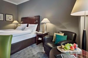 a hotel room with a bed and a chair at Lindner Hotel Cologne City Plaza, part of JdV by Hyatt in Cologne