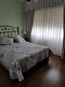 1 dormitorio con 1 cama con manta blanca y ventana en Casa Camiño dos Faros, 