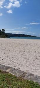 a sandy beach with a large body of water at Casa Camiño dos Faros 