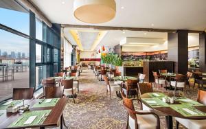 un restaurant avec des tables et des chaises et une grande fenêtre dans l'établissement Lindner Hotel Bratislava, part of JdV by Hyatt, à Bratislava