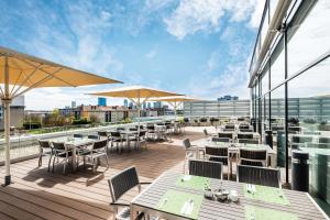 a deck with tables and chairs and umbrellas on a building at Lindner Hotel Bratislava, part of JdV by Hyatt in Bratislava