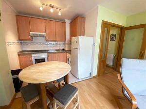 a kitchen with a table and a white refrigerator at "EL TAYUELO" in Posada de Llanes +7 photos