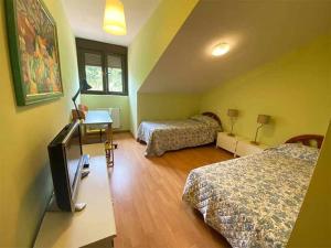 a bedroom with two beds and a tv in a room at "EL TAYUELO" in Posada de Llanes