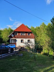 una casa con techo rojo y un coche aparcado delante en Guest house Wolf II en Plitvička Jezera