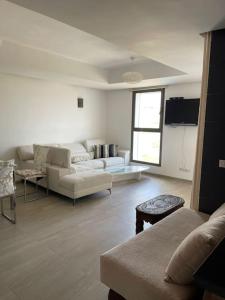 uma sala de estar com mobiliário branco e uma janela em Appartement De Luxe à Taghazout em Agadir