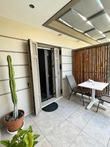 een patio met een tafel en stoelen en een cactus bij Luxury Studio Artemida in Artemida