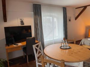 a room with a table and a desk and a television at Hotel Luther Birke Wittenberg in Lutherstadt Wittenberg