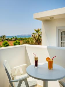 a table and chairs on a balcony with a drink at Divina Seaside Apartments by Estia in Gouves