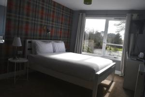 a bedroom with a white bed and a window at Lunan House in Arbroath