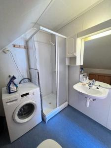 małą łazienkę z pralką i umywalką w obiekcie Odda City Apartments w mieście Odda
