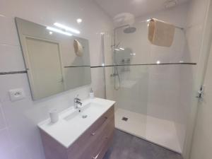 La salle de bains blanche est pourvue d'un lavabo et d'une douche. dans l'établissement La Sout à découverte, à La Souterraine