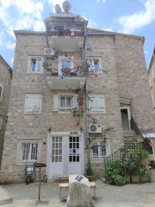 a large brick building with a balcony on top of it at Attic Old Town Apartment in Budva