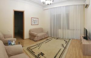 Central Baku Luxury Boulivard Apartment في باكو: غرفة معيشة مع كرسي أريكة وتلفزيون