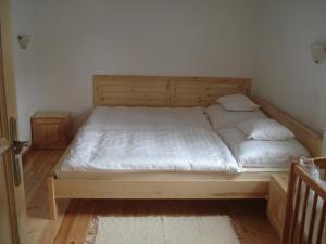 Una cama con sábanas blancas y almohadas en un dormitorio en Gerendás Vendégház en Sótony