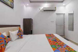 a bedroom with a large white bed with colorful pillows at FabHotel A One Inn in Lucknow
