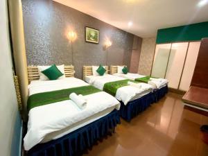 a room with three beds with green and white at Moonlight Villa in Phnom Penh