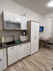 uma cozinha com armários brancos e um micro-ondas em MONDO - self check in em Osijek
