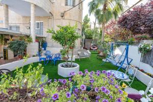 un patio con un jardín con un árbol y sillas en Mike's House Jerusalem en Jerusalem