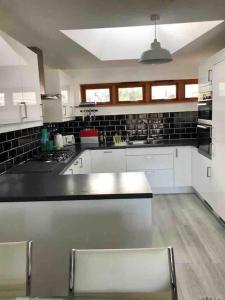 a large kitchen with white cabinets and black tiles at 2 Dorset Mews in Lyme Regis