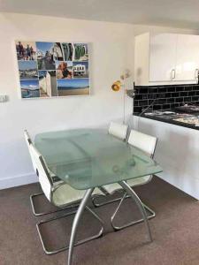a glass table and two chairs in a kitchen at 2 Dorset Mews in Lyme Regis