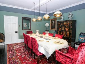 a dining room with a table and red chairs at The Farmhouse in North Walsham