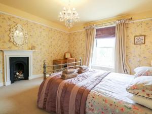 a bedroom with a bed with a fireplace and a chandelier at The Farmhouse in North Walsham