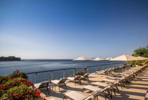a row of chairs and umbrellas next to the water at Boutique & Design Hotel Navis - Small Luxury Hotels of the World in Opatija
