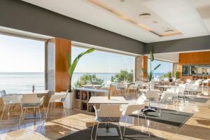 Suites del Mar by Melia في أليكانتي: غرفة طعام بها طاولات وكراسي ونوافذ كبيرة