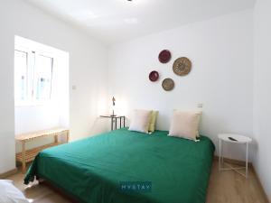 ein Schlafzimmer mit einem grünen Bett und einer weißen Wand in der Unterkunft MyStay - Casa Esposende 