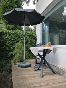 een tafel met een paraplu en een stoel op een veranda bij Appartementhaus Martel - Adults Only in Travemünde