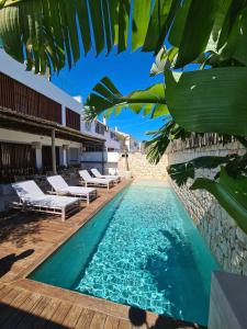 a pool with chaise lounge chairs next to a building at S´Estancia Suites in Es Mercadal