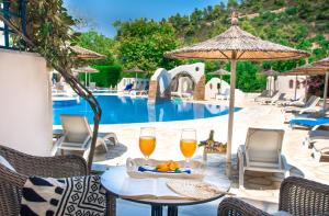 un tavolo con due bicchieri di vino accanto a una piscina di Acrotel Athena Pallas a Elia