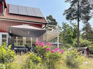 una casa con techo solar y flores delante de ella en 6 person holiday home in VRETA KLOSTER en Vreta Kloster