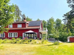 une maison rouge avec des panneaux solaires en haut dans l'établissement 6 person holiday home in VRETA KLOSTER, à Vreta Kloster