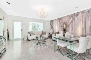 una sala de estar con muebles blancos y una lámpara de araña. en Stunning 2bdr2bath Steps To The Beach, en Fort Lauderdale