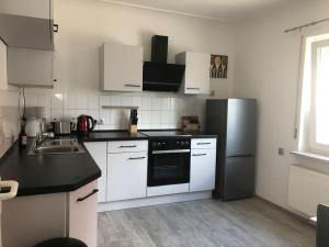 a kitchen with white cabinets and a black and white refrigerator at Family House Bibertal in Bibertal 