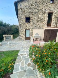 a stone house with a stone patio and flowers at Casa Dell'Angelo Cherubino Monolocale in Castelnuovo Magra