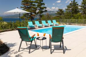 - une piscine avec des chaises, une table et un parasol dans l'établissement Villa Gloria, à Šilo
