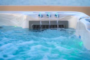 a bathtub filled with water with four faucets at Lalari Beach Suites in Vari